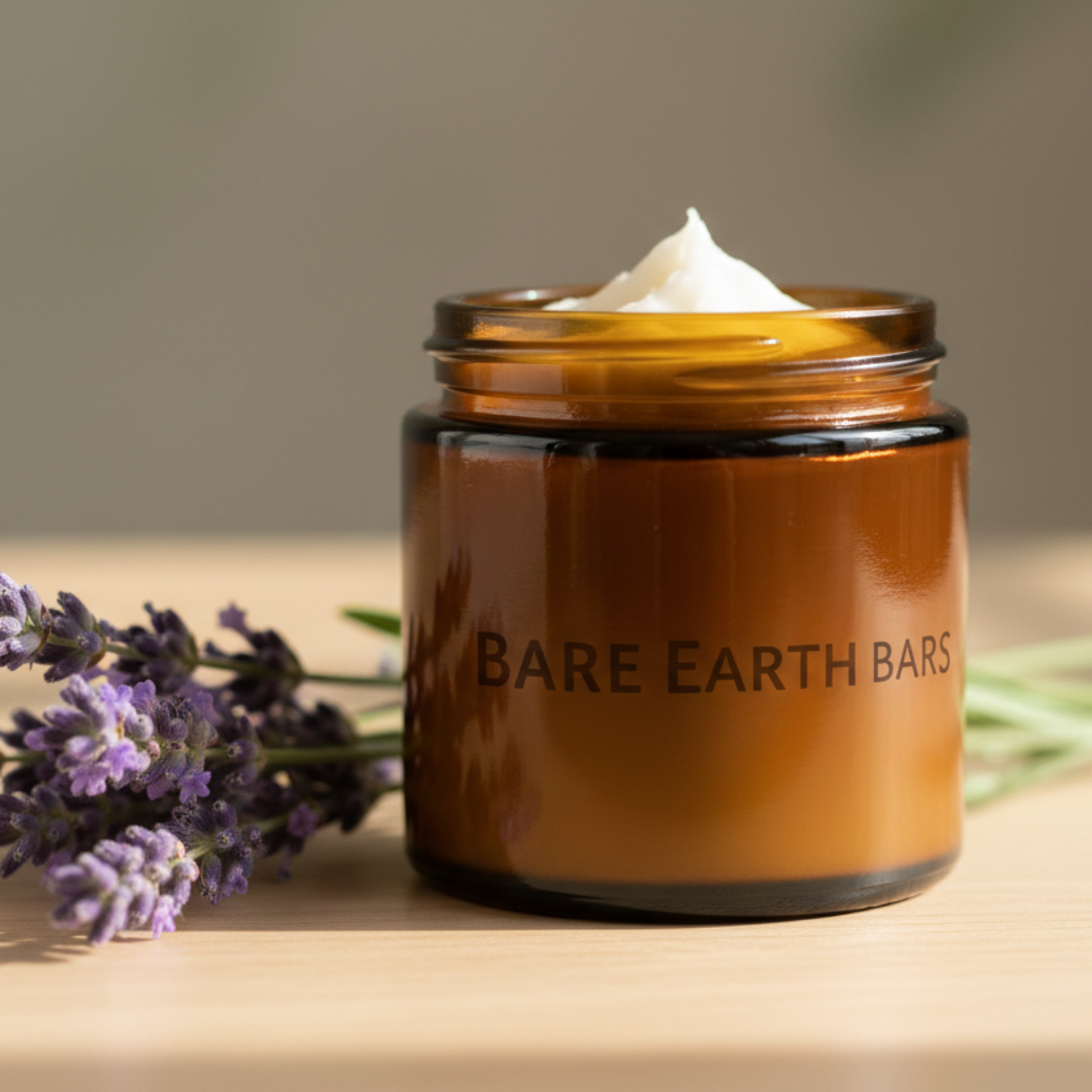 lavender body butter, with an amber glass jar, white body butter in the jar, "Bare Earth Bars" printed on the jar
